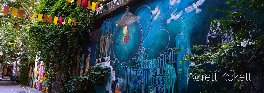 Belebte Straßengrafik an einer muralen Wand mit bunten Murals, Drachensymbolen und Pflanzen, hängende Wimpelketten.